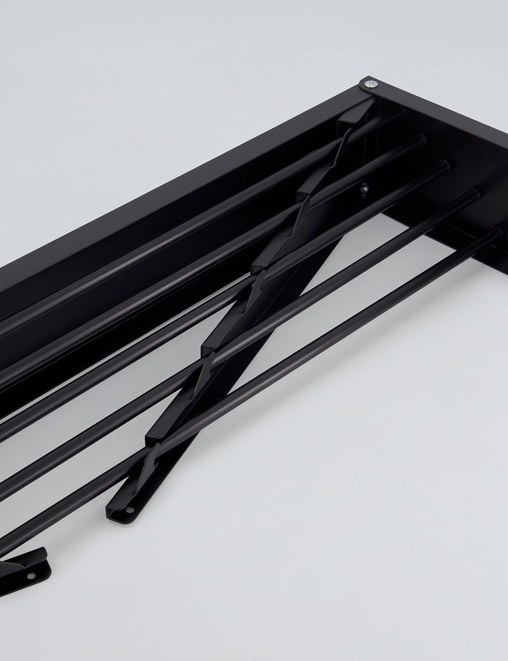 Black wall mounted drying rack with laundry hanging to dry